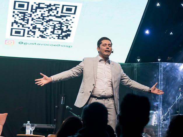 Gustavo Coelho de braços abertos durante uma palestra